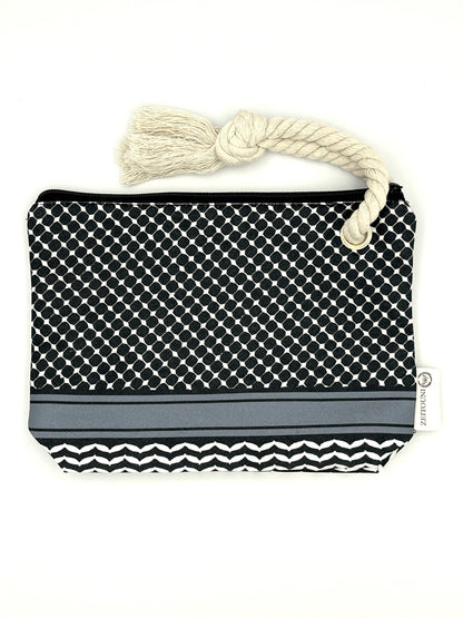Black makeup bag with beige rope against a white background. Bag is designed with a keffiyeh pattern on the pouch and a ZEITOUNI logo tag. 