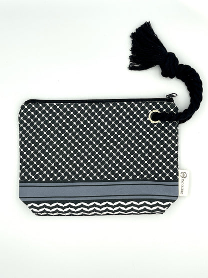Black makeup bag with black rope handle against a white backround. Bag is patterned with a black keffiyeh pattern and a ZEITOUNI logo tag.